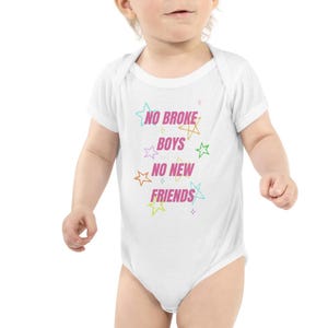 May include: A white short-sleeved baby bodysuit featuring the pink text NO BROKE BOYS NO NEW FRIENDS centered on the chest. The design is surrounded by small, colorful outlined star shapes in shades of blue, yellow, green, orange, and purple.