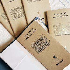 Puede incluir: Una taza de cerámica blanca con un asa negra y el texto "But First, Coffee" en negro, en negrita. La taza está sobre una superficie blanca.