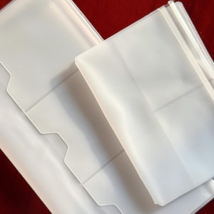 以下が含まれることがあります： 赤色の表面に配置された、いくつかの透明で半透明のプラスチックカードホルダー。 ホルダーは、ポケットとノッチ付きのエッジを備えた長方形の形状をしています。 プラスチックは滑らかで、新品のようです。