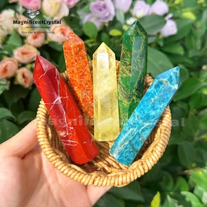Könnte beinhalten: Eine Sammlung farbiger Kristallspitzen in einem geflochtenen Korb. Die Kristalle sind rot, orange, gelb, grün und blau. Der Text "MagnificentCrystal" und "Your Key to Vibrant Living" sind sichtbar.