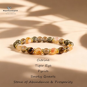 May include: A beaded bracelet featuring citrine, tiger eye, pyrite, and smoky quartz stones. The bracelet has gold-colored spacers between the beads. The text on the image reads "Stone of Abundance & Prosperity."