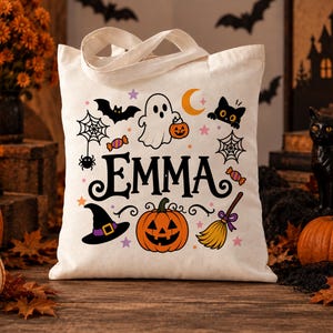 Può includere: Una borsa tote in tela color crema con il nome EMMA in grandi lettere nere. Il design presenta illustrazioni colorate a tema Halloween con un fantasma, una zucca, un cappello da strega, una scopa, un gatto nero, pipistrelli e ragnatele.