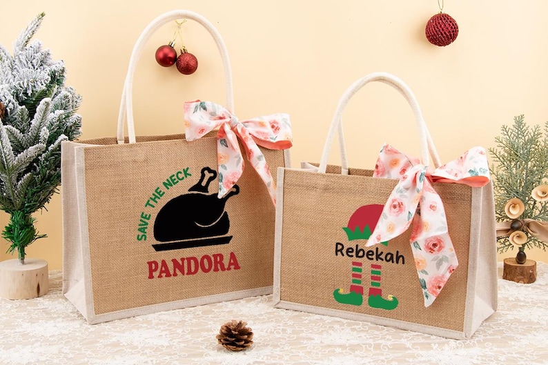 May include: Two burlap tote bags with white handles and floral bows. One bag has a black turkey graphic and the name "Pandora" in red. The other bag features an elf graphic and the name "Rebekah".