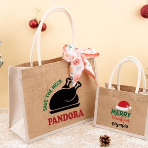 May include: Two jute tote bags with white handles. The larger bag has a black turkey graphic and the text "SAVE THE NECK" and "PANDORA". The smaller bag says "Merry Christmas Olympia" with a Santa hat.