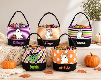 May include: Five cylindrical fabric baskets with black handles and black bases, each personalized with names Kathryn, Freya, Tabitha, Sophia, and Amelia. The baskets feature colorful patterns including stripes and polka dots, decorated with ghost and monster graphics.