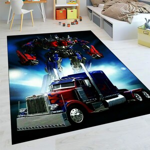 May include: A rectangular rug featuring a red, blue, and silver semi-truck with a robot figure in the background. The rug has a black border and a blue and white sky-like background.