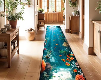 Puede incluir: Una alfombra rectangular larga con una escena submarina azul y blanca. La alfombra presenta peces naranja y rojos nadando entre arrecifes de coral y algas marinas. La alfombra es perfecta para agregar un toque de fantasía a un pasillo o entrada.