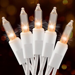 May include: A string of five clear incandescent light bulbs with white bases and white electrical cords. Each bulb emits a warm, glowing light with a starburst effect, set against a dark, out-of-focus background with bokeh lights.