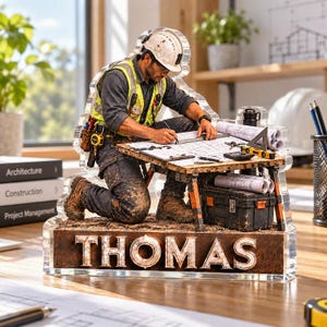 May include: A clear acrylic desk ornament featuring a 3D-style illustration of a construction worker in a hard hat and high-visibility vest kneeling while reviewing blueprints on a wooden table. The base displays the name THOMAS in bold letters.