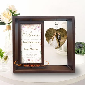 May include: A dark brown wooden wedding frame with a rotating sign that reads "Welcome to the wedding of Ferdy Martinez & Tessa Morales" and a heart-shaped photo of a couple dancing. The date is August 25, 2026, in Las Vegas, NV.