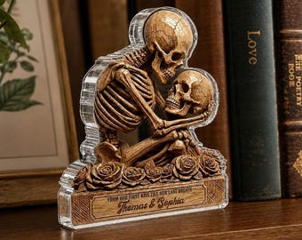 May include: A clear acrylic plaque featuring a tan, textured skeleton couple embracing above a row of carved roses. The base includes the engraved text: FROM OUR FIRST KISS TILL OUR LAST BREATH, followed by the names Thomas & Sophia in script font.