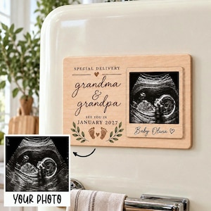 May include: A rectangular light wood magnet featuring the text SPECIAL DELIVERY grandma & grandpa SEE YOU IN JANUARY 2027 with a small heart, baby footprints, and green leaf illustrations, plus a square frame holding a baby ultrasound image.