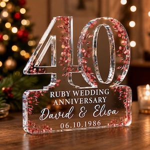May include: A clear acrylic plaque shaped as the number 40, featuring embedded red floral accents. The base displays the text RUBY WEDDING ANNIVERSARY, the names David & Elisa, and the date 06.10.1986 in white lettering.