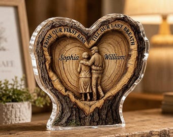 May include: A heart-shaped acrylic plaque featuring a wood grain texture and a relief sculpture of two figures standing together. The text "FROM OUR FIRST KISS TILL OUR LAST BREATH" is engraved at the top, with the names "Sophia" and "William" centered.