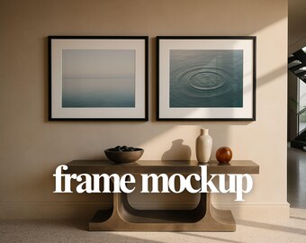 May include: Two framed art prints with black frames hang above a console table. One print shows a seascape, the other a water ripple. A ceramic vase, a wooden bowl with dark objects, and a decorative sphere are on the table. The text "frame mockup" is across the table.