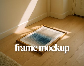 Könnte beinhalten: Ein rechteckiger Holzrahmen mit einem Aquarelldruck von blauen und beigen Wellen, der auf einem hellen Holzboden liegt. Der Text "frame mockup" ist in Weiß dargestellt. Die Szene wird von natürlichem Licht beleuchtet.