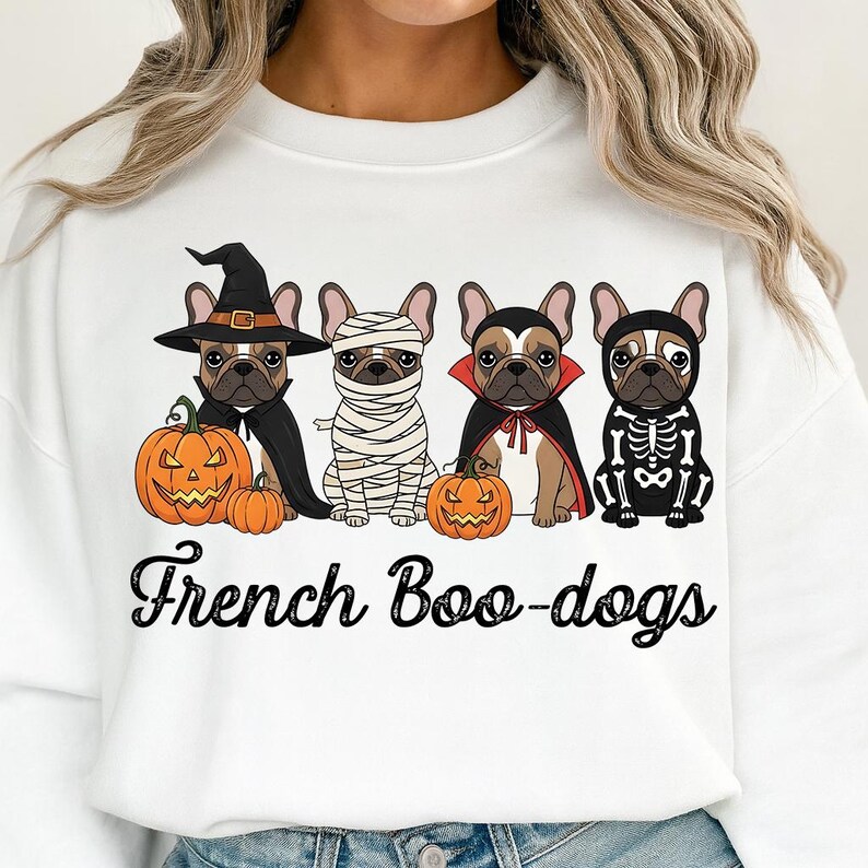 May include: White sweatshirt featuring four French Bulldogs dressed in Halloween costumes. One dog is a witch, another a mummy, a third a vampire, and the last a skeleton. The words "French Boo-dogs" are printed below the dogs.