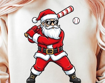 Puede incluir: Ilustración de Papá Noel en posición de béisbol, con gafas de sol, traje rojo y cinturón negro. Sostiene un bate de béisbol con rayas rojas y blancas, con una pelota cerca. El diseño está en una sudadera crema.