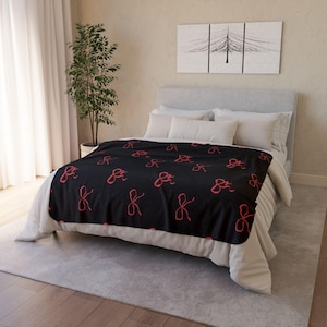 Könnte beinhalten: Schwarze Fleece-Decke mit einem sich wiederholenden Muster aus roten Schleifen.