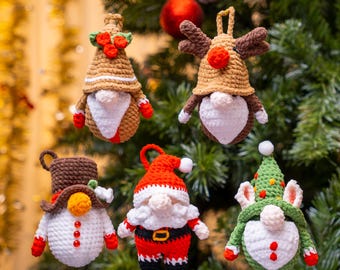 May include: Five handmade crochet Christmas ornaments in the shape of gnomes, hanging on a Christmas tree. The gnomes have various hats and outfits in red, brown, white, and green. Each ornament is approximately 4 inches tall.