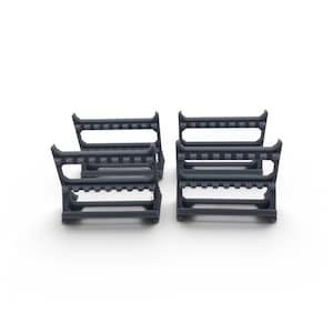 Puede incluir: Cuatro soportes de plástico gris oscuro para correas de reloj. Cada soporte tiene una base rectangular, una serie de pequeñas clavijas en la parte superior y lados curvos. Los soportes están dispuestos en una formación cuadrada sobre un fondo blanco.