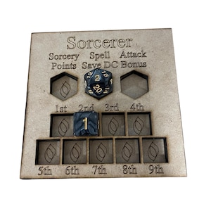 Pode incluir: Um tabuleiro quadrado de madeira para rastrear estatísticas de jogo de feiticeiro, com texto gravado incluindo Sorcery Points, Spell Save DC e Attack Bonus. O tabuleiro tem recortes para dados, com um dado de vinte lados e um de seis lados.