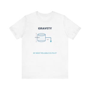 May include: A white short-sleeve t-shirt featuring a dark blue graphic with the word GRAVITY at the top. Below is a blue diagram of a cylinder labeled PROCESS with an arrow pointing OUT. The text MY MOST RELIABLE CO-PILOT is printed in blue.