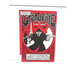 May include: A red hardcover book titled "Grandville" by Bryan Talbot. The cover features a black and white illustration of a badger detective holding two guns, with the Eiffel Tower in the background. The book is a detective story.
