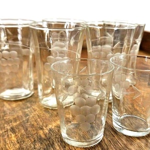 以下が含まれることがあります： ブドウの房のデザインがエッチングされた、透明なグラス6個セット。木製の表面に配置され、エレガントでヴィンテージなスタイルを表現しています。水、ジュース、その他の飲み物の提供に最適です。