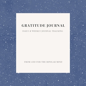 May include: A gratitude journal with a white rectangular design on a blue speckled background. The text on the journal reads "GRATITUDE JOURNAL" and "DAILY & WEEKLY JOURNAL TRACKING". The bottom of the journal reads "FROM AND FOR THE BIPOLAR MIND".
