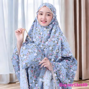 May include: A light blue prayer garment set with a floral pattern of white and pink flowers. The set includes a head covering and a matching drawstring bag. The edges are trimmed with a delicate lace.