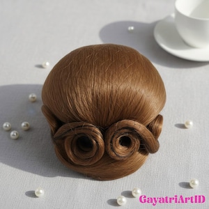 May include: A brown wig with a classic updo style, featuring two curled side pieces. The wig is set against a neutral background with scattered faux pearls and a white teacup. The wig's color is a warm, medium brown.