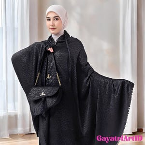 May include: A black patterned cloak and matching handbag are shown. The cloak has wide sleeves and a hood, and the handbag has a gold chain strap. The outfit is made of a textured fabric. The image includes the text "GayatriArtID".