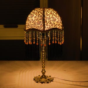 Ręcznie robiona lampa stołowa z nadrukiem w panterkę: mosiężna podstawa i frędzle, lampa prezentowa