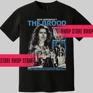 Peut inclure: T-shirt noir avec un imprimé graphique du film "The Brood" de David Cronenberg. Le graphique représente des personnages du film, dont une femme aux longs cheveux noirs, un homme barbu et une jeune fille. Le texte "The Nightmares Will Follow" et "They're Waiting For You!" font également partie du graphique.