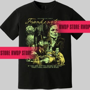 May include: Black t-shirt featuring a graphic from Guillermo del Toro's Frankenstein. The design includes illustrations of characters and the film's title. The text "IF YOU ARE NOT TO AWARD ME LOVE THEN I WILL INDULGE IN RAGE" is also included.