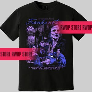May include: Black t-shirt featuring a graphic from Guillermo del Toro's "Frankenstein." The design includes characters and the film's title in a stylized font. The quote "IF YOU ARE NOT TO AWARD ME LOVE THEN I WILL INDULGE IN RAGE" is also present.