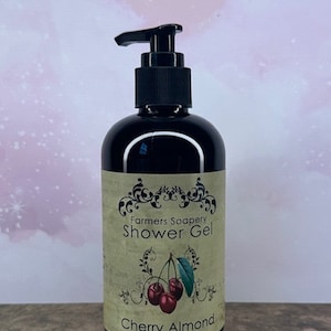 May include: A black bottle of cherry almond shower gel with a pump dispenser. The label is cream colored with black text that reads "Farmers Soapery Shower Gel" and "Cherry Almond".