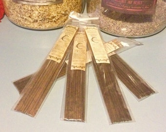 May include: Several bundles of incense sticks in clear plastic packaging. Each package has a label with the words "Incense Moroccan Spice" and a crescent moon design. The incense sticks are a dark brown color.