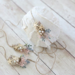 K&ouml;nnte beinhalten: Ein Set aus zwei Baby-Stirnb&auml;ndern f&uuml;r Neugeborene mit rustikalem, nat&uuml;rlichem Thema. Jedes Stirnband ist mit einem kleinen Strau&szlig; aus Kunstblumen, Perlen und goldenen Sternchen verziert. Die Stirnb&auml;nder sind mit einem braunen Bindfaden gebunden.