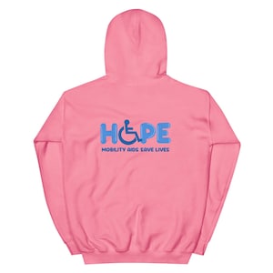 Könnte beinhalten: Ein hellrosa Kapuzenpullover mit Kapuze. Auf der Rückseite steht das Wort "HOPE" in blauen Buchstaben, mit einem Rollstuhlsymbol in dem "O". Darunter steht der Text "MOBILITY AIDS SAVE LIVES".