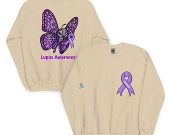 May include: Beige sweatshirt featuring a purple butterfly with a purple ribbon and the words "Lupus Awareness". The front of the sweatshirt has a purple awareness ribbon. A small blue ribbon is on the sleeve.