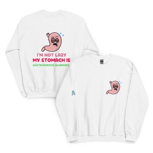 May include: White sweatshirt with a cartoon stomach graphic. The graphic on the back says "I'M NOT LAZY MY STOMACH IS GASTROPARESIS AWARENESS". The front has a smaller stomach graphic and a blue ribbon. A comfortable, casual top.