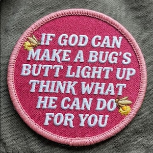 May include: A round, pink embroidered patch with the text "IF GOD CAN MAKE A BUG'S BUTT LIGHT UP THINK WHAT HE CAN DO FOR YOU" in white. The patch has a light pink border and two embroidered fireflies.