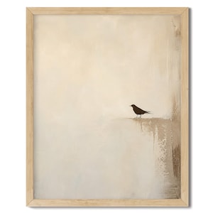 May include: A framed wall art print featuring a small black bird silhouette perched on a textured, light beige and cream abstract background. The artwork is enclosed in a simple, light-toned wooden frame with a clean, rectangular border design.