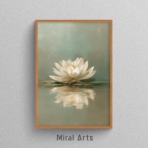May include: A framed art print featuring a white lotus flower floating on water. The flower is reflected in the water below. The background is a soft, muted green. The frame is a light brown color. The text "Miral Arts" is at the bottom.