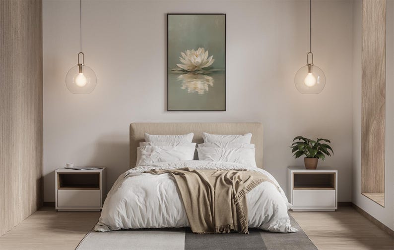 May include: Bedroom interior with a large bed, white bedding, and a tan throw blanket. A framed artwork of a white flower is above the bed. Two pendant lights with round glass shades hang on either side of the bed. A small potted plant sits on a nightstand.