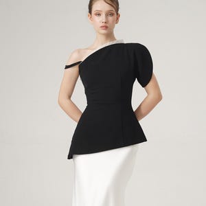 May include: A formal black and white dress. The top is black with a one-shoulder design and a peplum waist. The skirt is a floor-length, white, satin-like material.