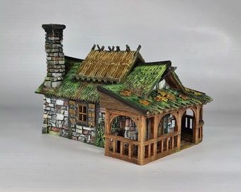 May include: A miniature stone cottage with a thatched roof, green moss, and a wooden porch. The cottage has a brick chimney and a small window with a wooden frame.