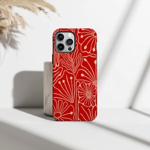 May include: A red phone case with a floral pattern. The case displays a repeating design of cream-coloured flowers and leaves on a solid red background. The case has cutouts for the camera and buttons.
